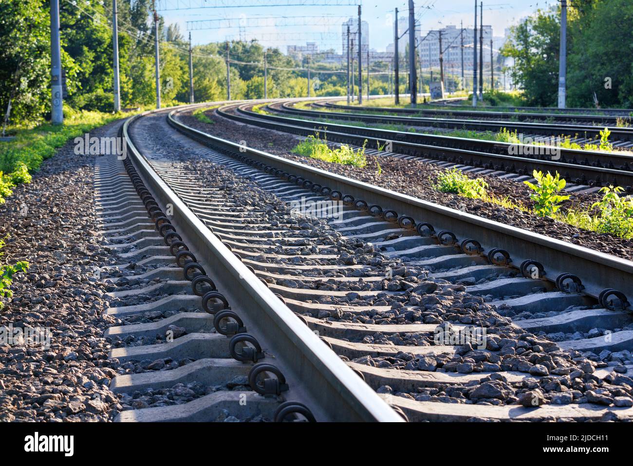 Gros plan sur les voies ferrées d'un chemin de fer à plusieurs voies s'étendant sur la distance avec la toile de fond d'une ville d'été matin à l'horizon. Banque D'Images
