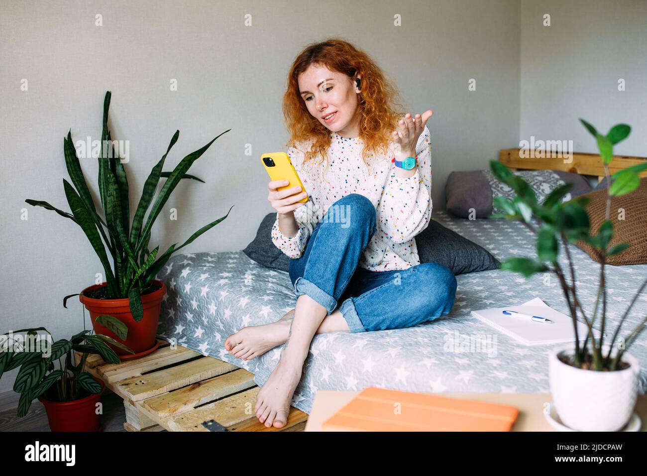 Jeune femme parlant sur un smartphone depuis sa maison lors d'un appel vidéo Banque D'Images