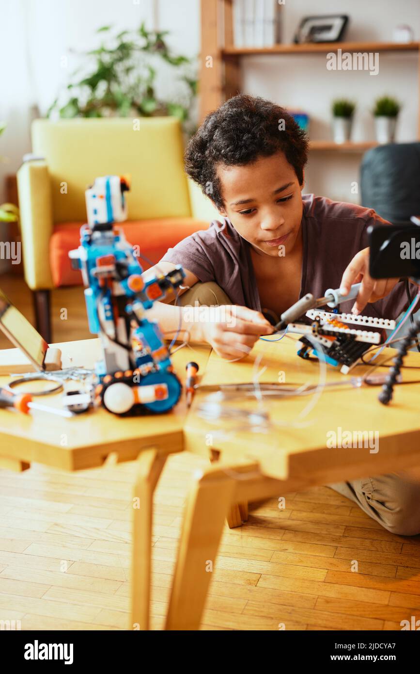 Un écolier africain dédié à la fabrication d'un robot à la maison pour les cours de sciences. Robotique à l'école Banque D'Images