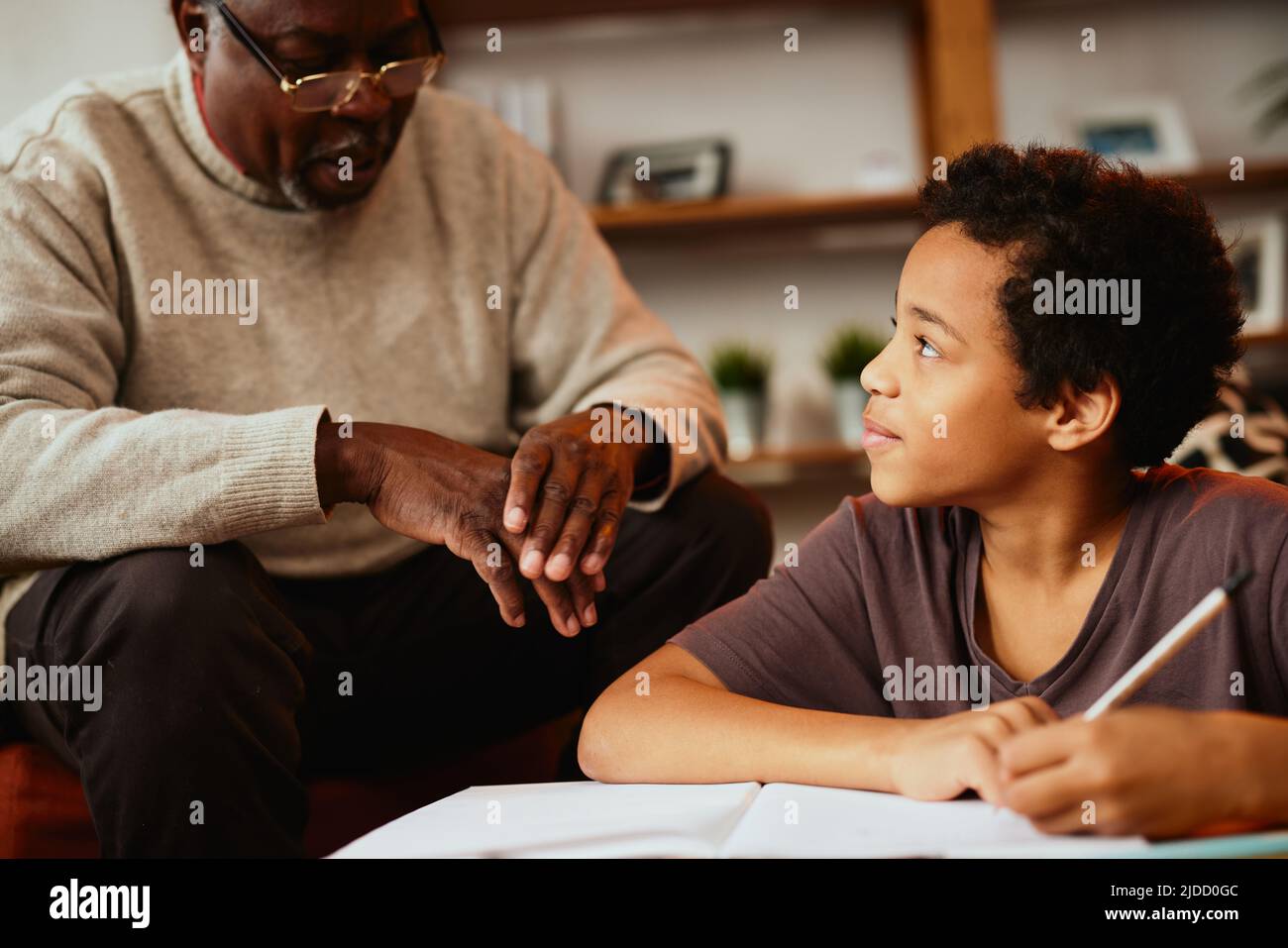 Un grand-père afro-américain est assis à la maison avec son petit-fils et l'aide pour ses devoirs. Banque D'Images