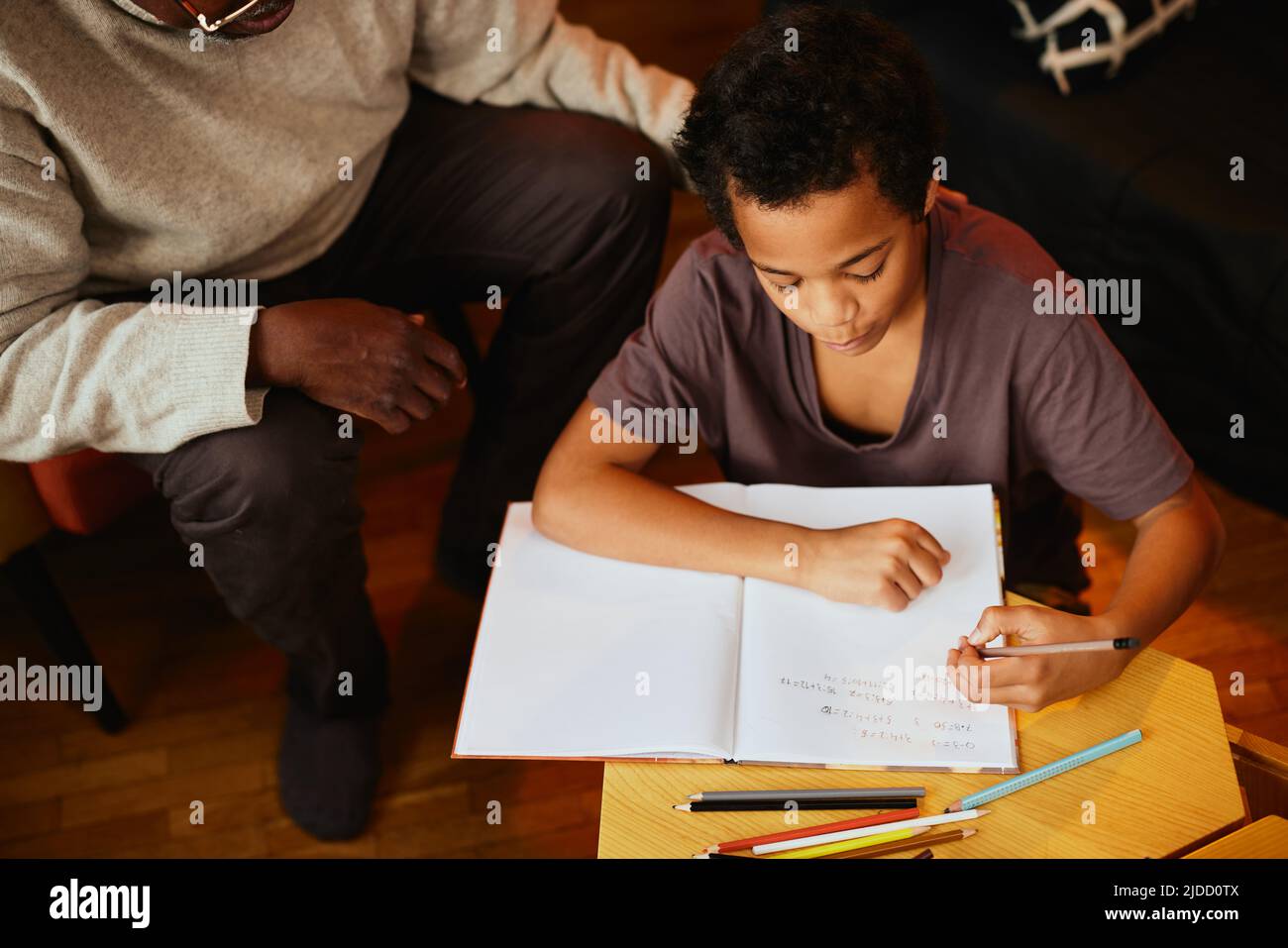 Un garçon africain intelligent qui fait ses devoirs de mathématiques avec un peu d'aide de son grand-père. Tutorat et éducation Banque D'Images