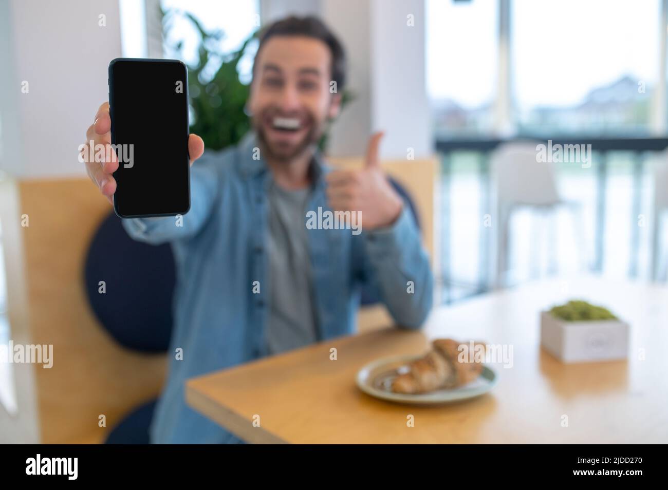 Homme montrant le smartphone et gestuelle ok Banque D'Images