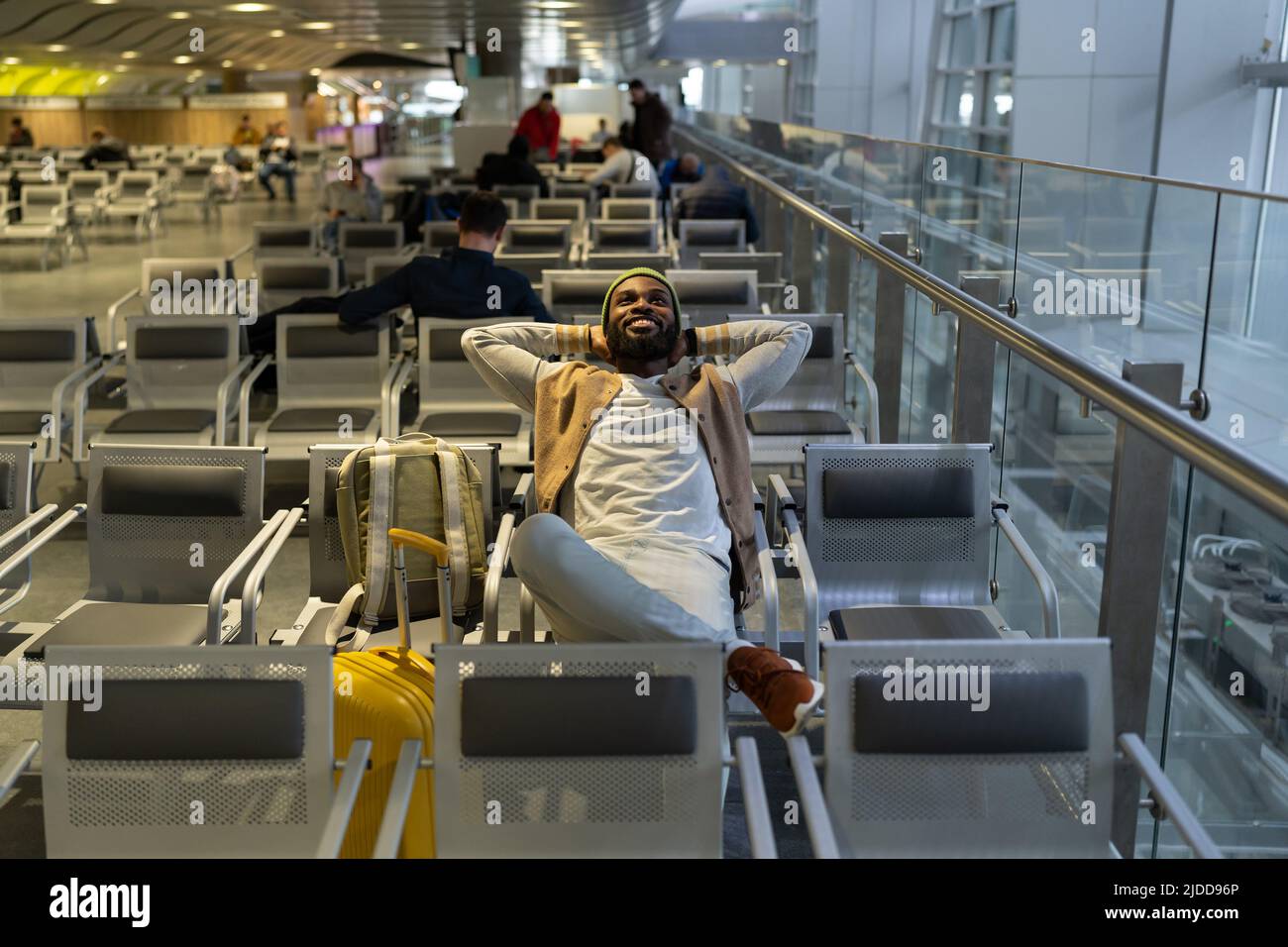 Joyeux noir assis à l'aéroport de repos, attendant l'atterrissage à bord regardant vers le haut, rêves de voyage. Banque D'Images