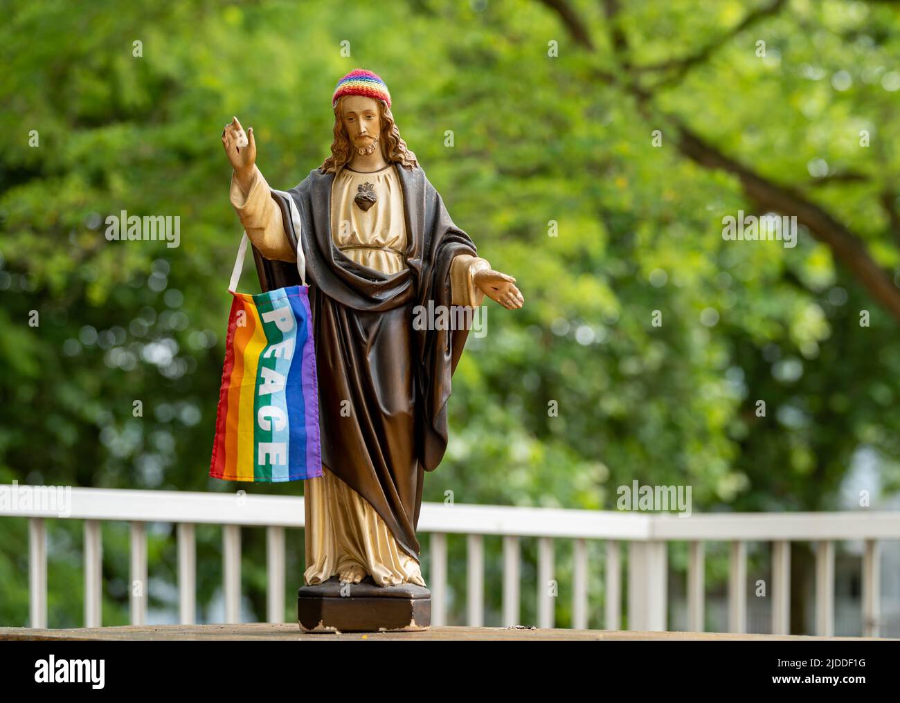 Statue de Jésus avec la casquette en tricot arc-en-ciel et le drapeau de fierté LGBT avec un signe de paix Banque D'Images