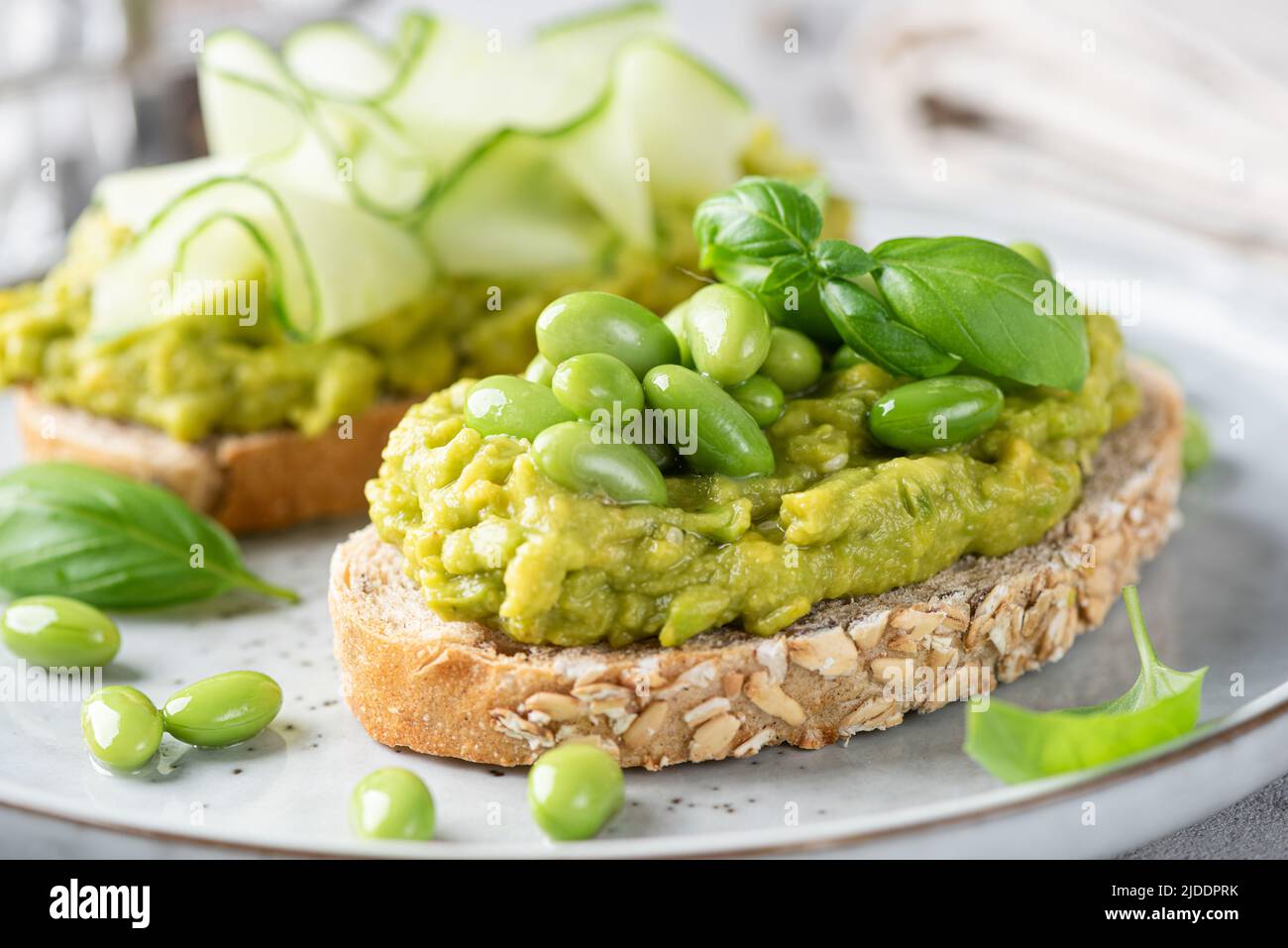 Toasts d'avocat verts frais avec haricots edamame et garnitures de concombre. Une alimentation propre, un concept alimentaire végétalien sain. Vue en gros plan Banque D'Images