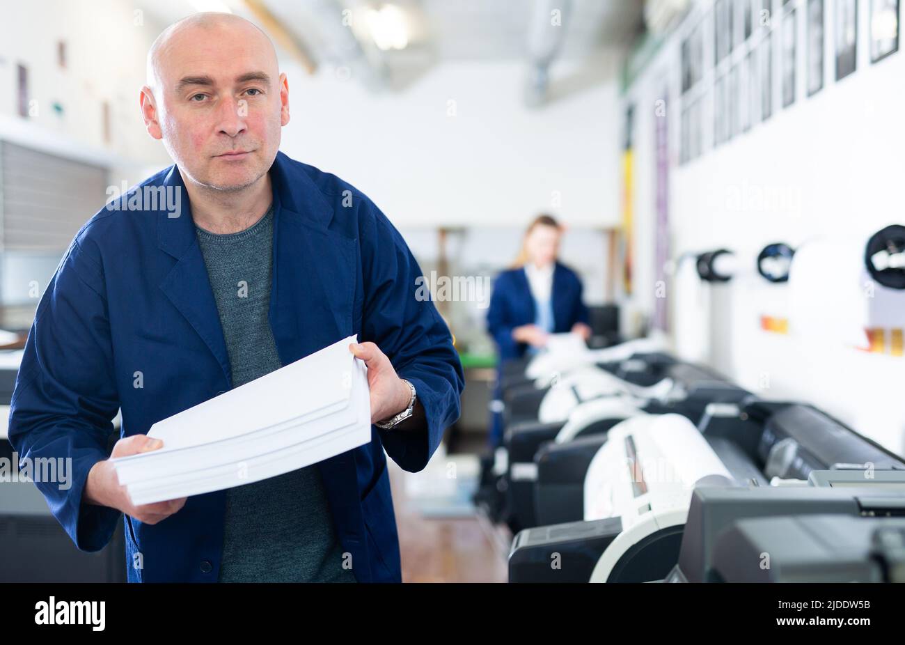 Portrait d'un employé de la maison d'impression avec pile de papier dans ses mains Banque D'Images