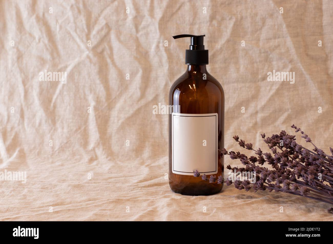 Videz le savon en verre ambré ou le flacon de shampooing sur un fond isolé. Soins de la peau ou concept de cheveux avec des cosmétiques naturels. Banque D'Images