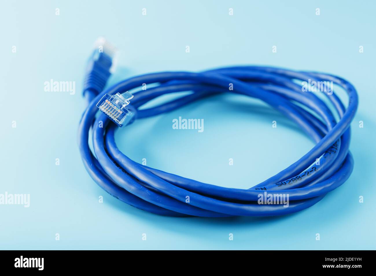 Une bobine de câble réseau Internet Ethernet RJ45 de catégorie 6 isolée sur fond bleu avec de l'espace libre Banque D'Images