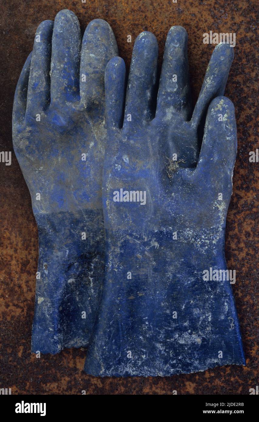 Gants en caoutchouc bleu extra-robustes recouverts de peinture ou de produits chimiques sur une tôle rouillée Banque D'Images