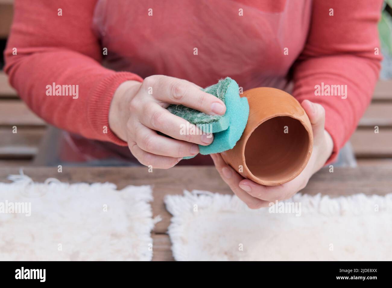 Mains de femme senior hydratant vase d'argile fait à la main par éponge pour colorer davantage avec glaçure Banque D'Images