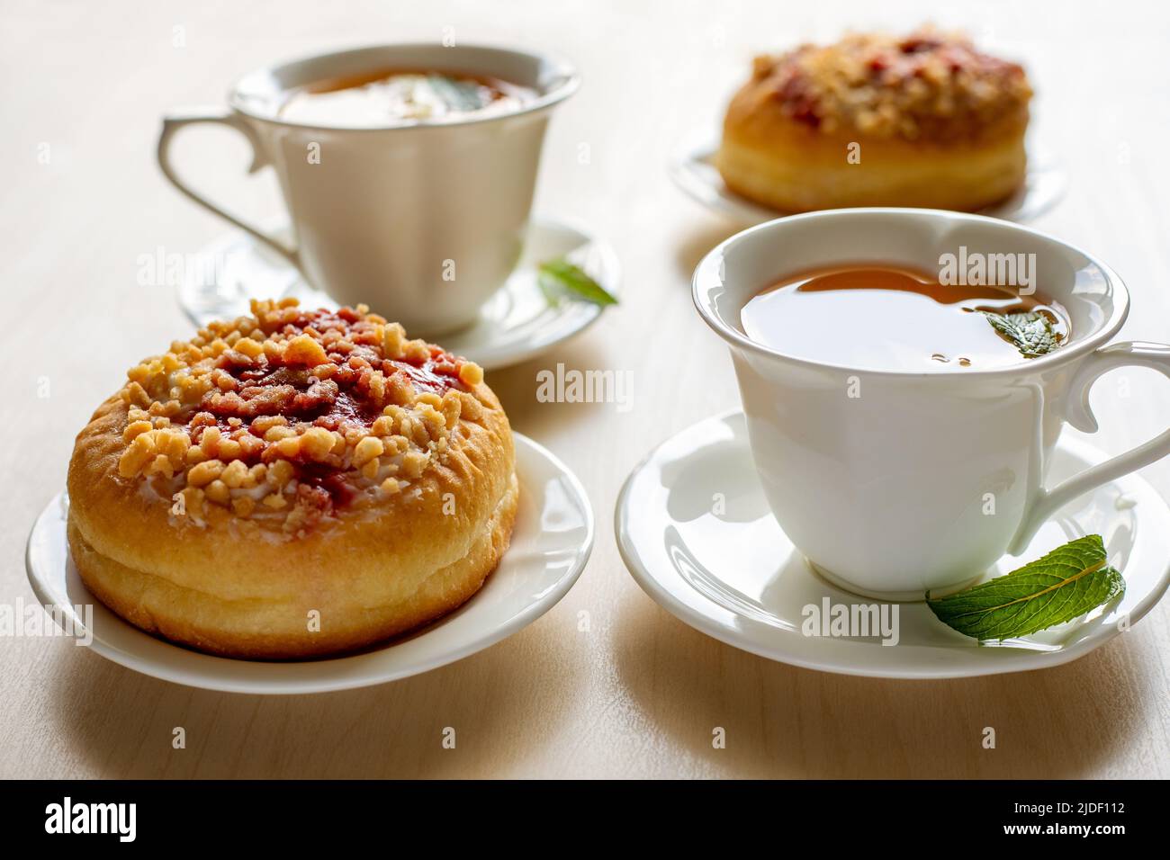 Beignets sucrés sur les assiettes et les tasses avec thé à la menthe sur la table en bois. Petit déjeuner savoureux. Banque D'Images