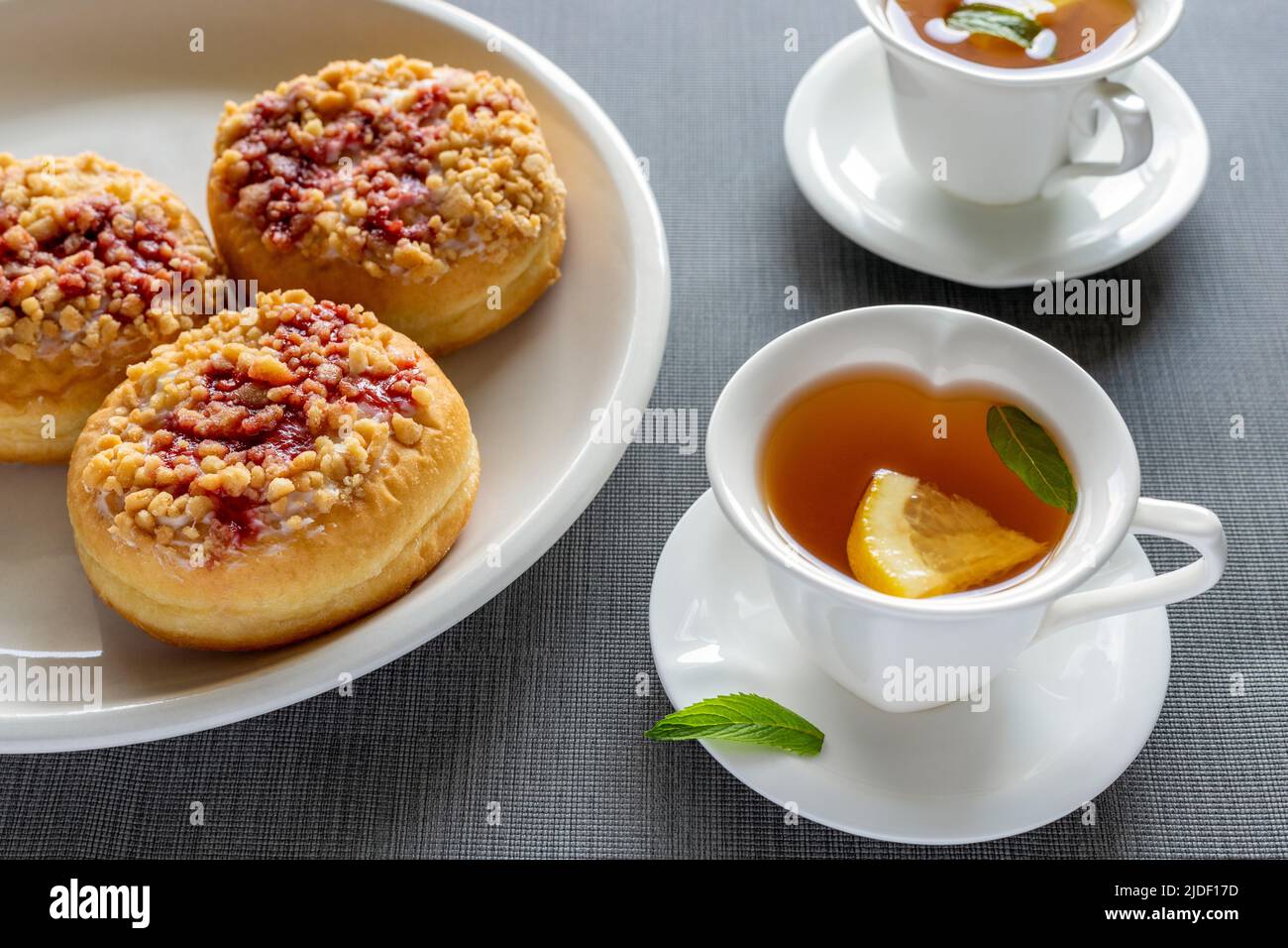 Beignets ronds doux sur les assiettes et petites tasses avec thé à la menthe sur la table. Petit déjeuner savoureux. Banque D'Images