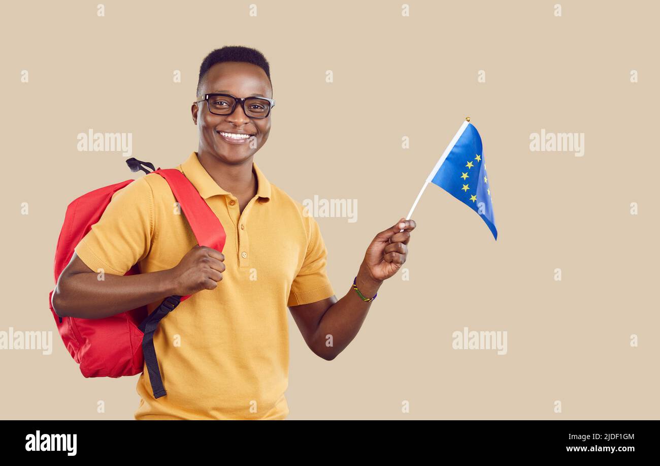 Joyeux étudiant afro-américain avec drapeau de l'Union européenne isolé sur fond beige clair. Banque D'Images