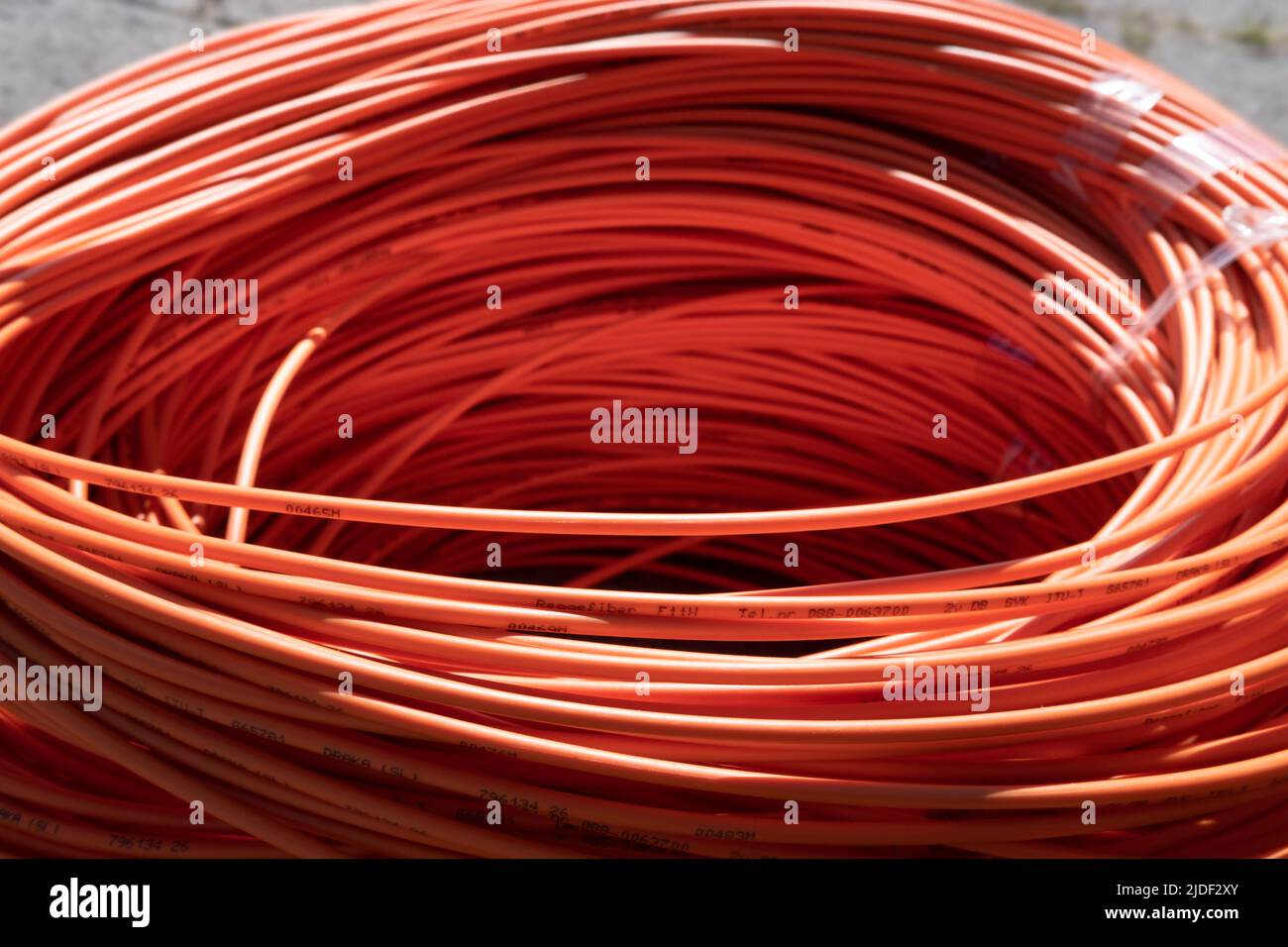 Faisceau de câbles en fibre optique orange enroulé dans la rue, prêt à entrer dans le sol. Internet rapide. Mise au point en avant Banque D'Images
