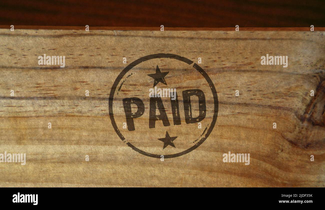 Timbre payé imprimé sur une boîte en bois. Concept de symbole de paiement par chèque, taxe et argent. Banque D'Images