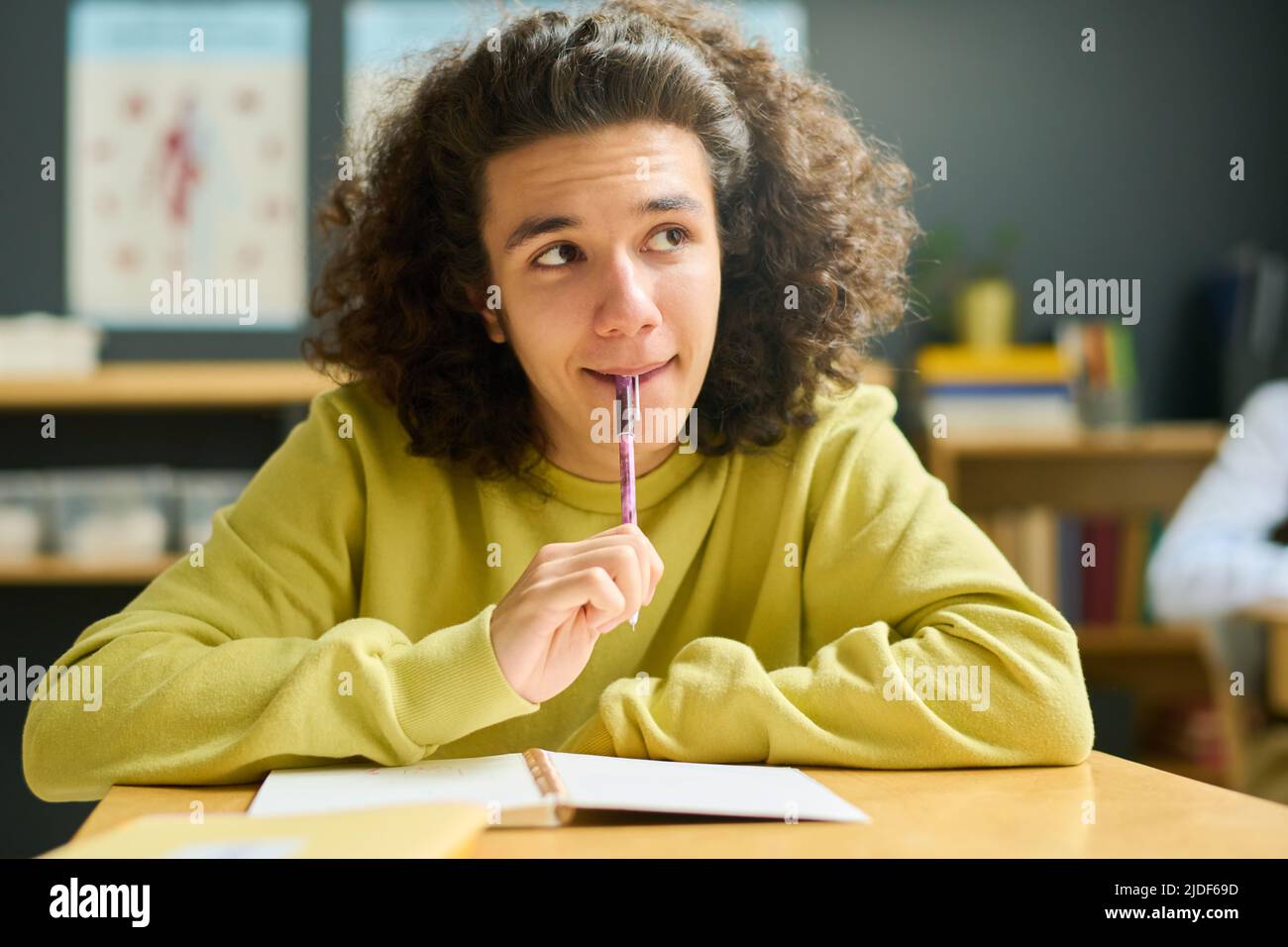 Adolescent intelligent gars en vêtements décontractés regardant l'enseignant expliquant le nouveau sujet par le tableau noir ou effectuant une tâche individuelle à la leçon Banque D'Images