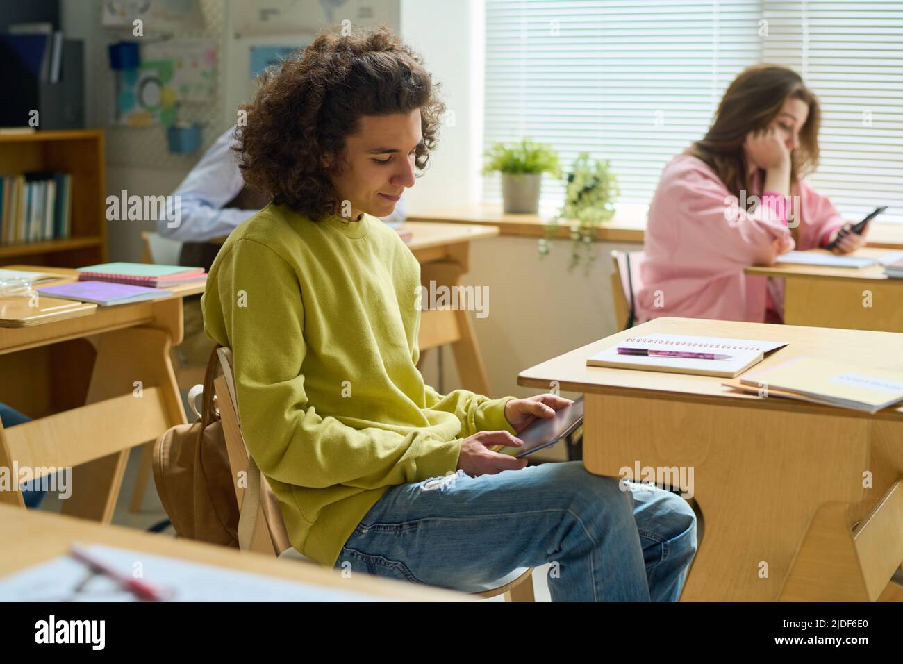 Un adolescent qui tient une tablette sur ses genoux à la recherche d'informations en ligne qui pourraient l'aider à effectuer son travail Banque D'Images