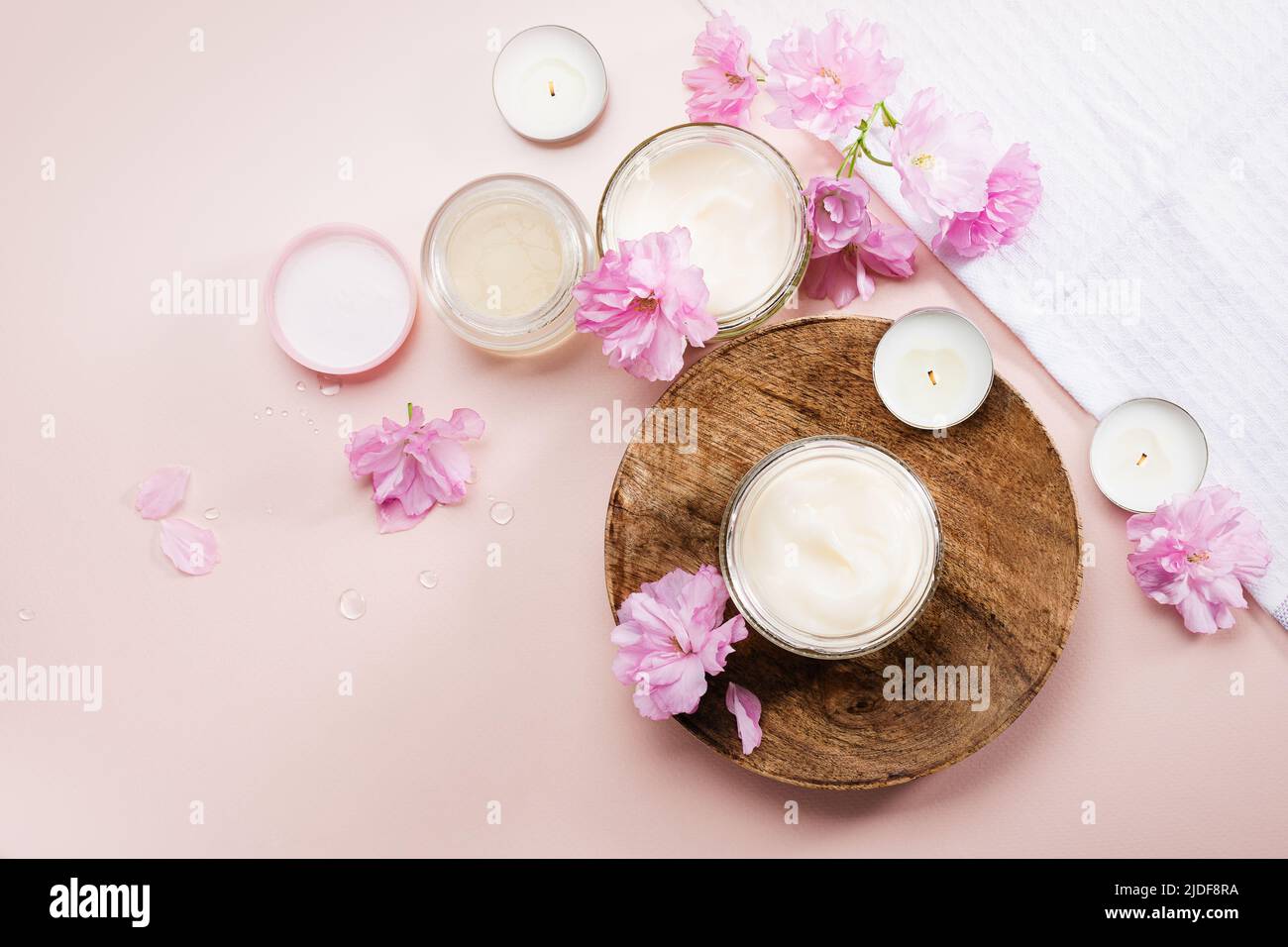 Crème de soin du corps et fleurs de cerisier rose. Pose à plat. Banque D'Images