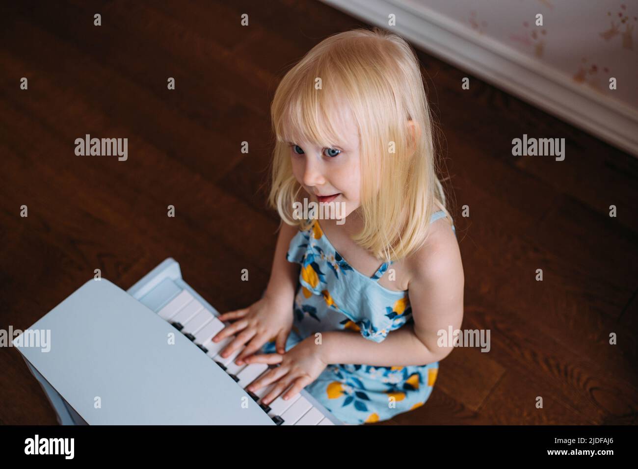 Une petite fille blonde joue un piano à la maison. Développement musical dans l'enfance Banque D'Images