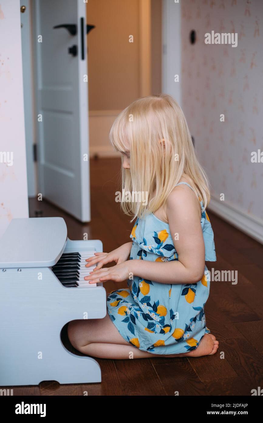 Une petite fille blonde joue un piano à la maison. Développement musical dans l'enfance Banque D'Images