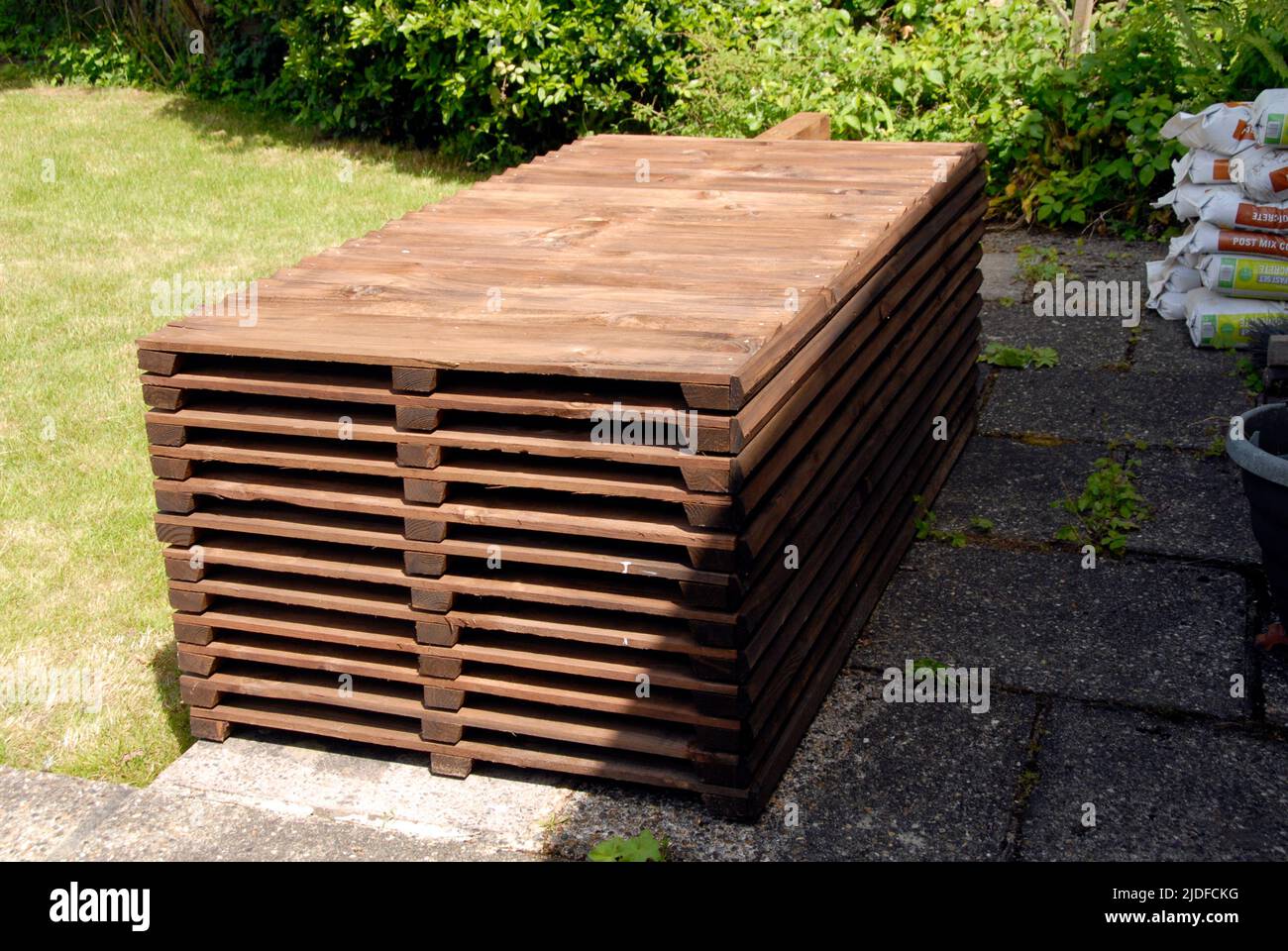 Pile de panneaux de clôture en bois, poteaux, planches de gravier et mélange de ciment, entreposée sur le patio prêt pour le remplacement de l'ancienne clôture de jardin domestique Banque D'Images