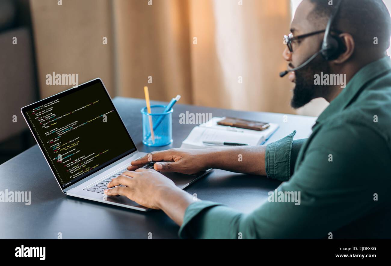 Vue de côté de la réussite african american IT Specialist, programmeur, siège dans un bureau moderne, travaillant sur le développement d'un site Web, application, écriture de codes et de code de données. Concept logiciel Banque D'Images