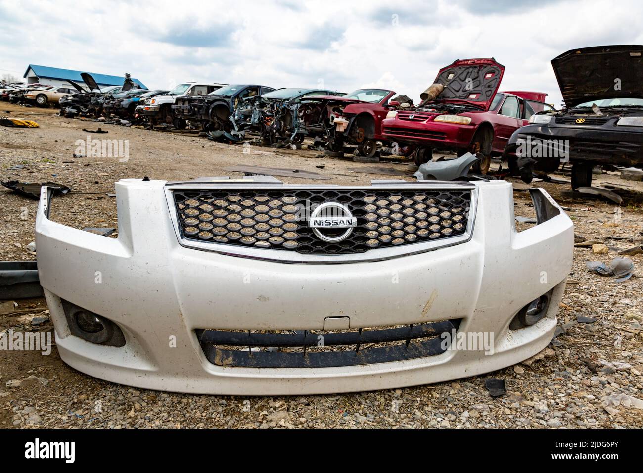 Le bouclier avant blanc d'une Nissan Sentra se trouve devant une rangée de voitures à risque au LKQ Pick Your part scrapyard à fort Wayne, Indiana, États-Unis. Banque D'Images