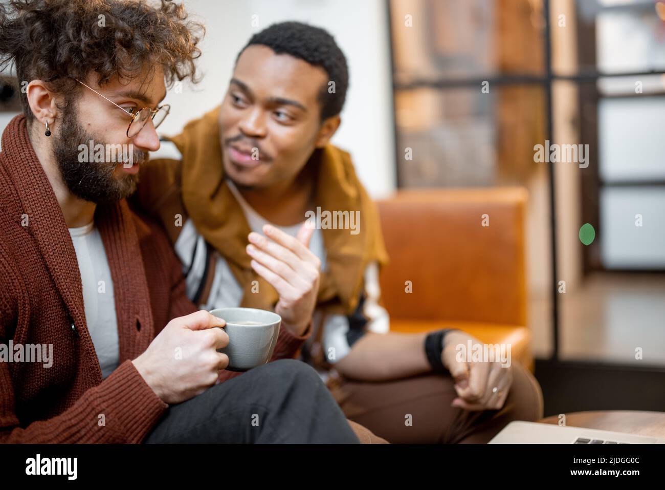 Un couple gay masculin parle sur un canapé à la maison Banque D'Images