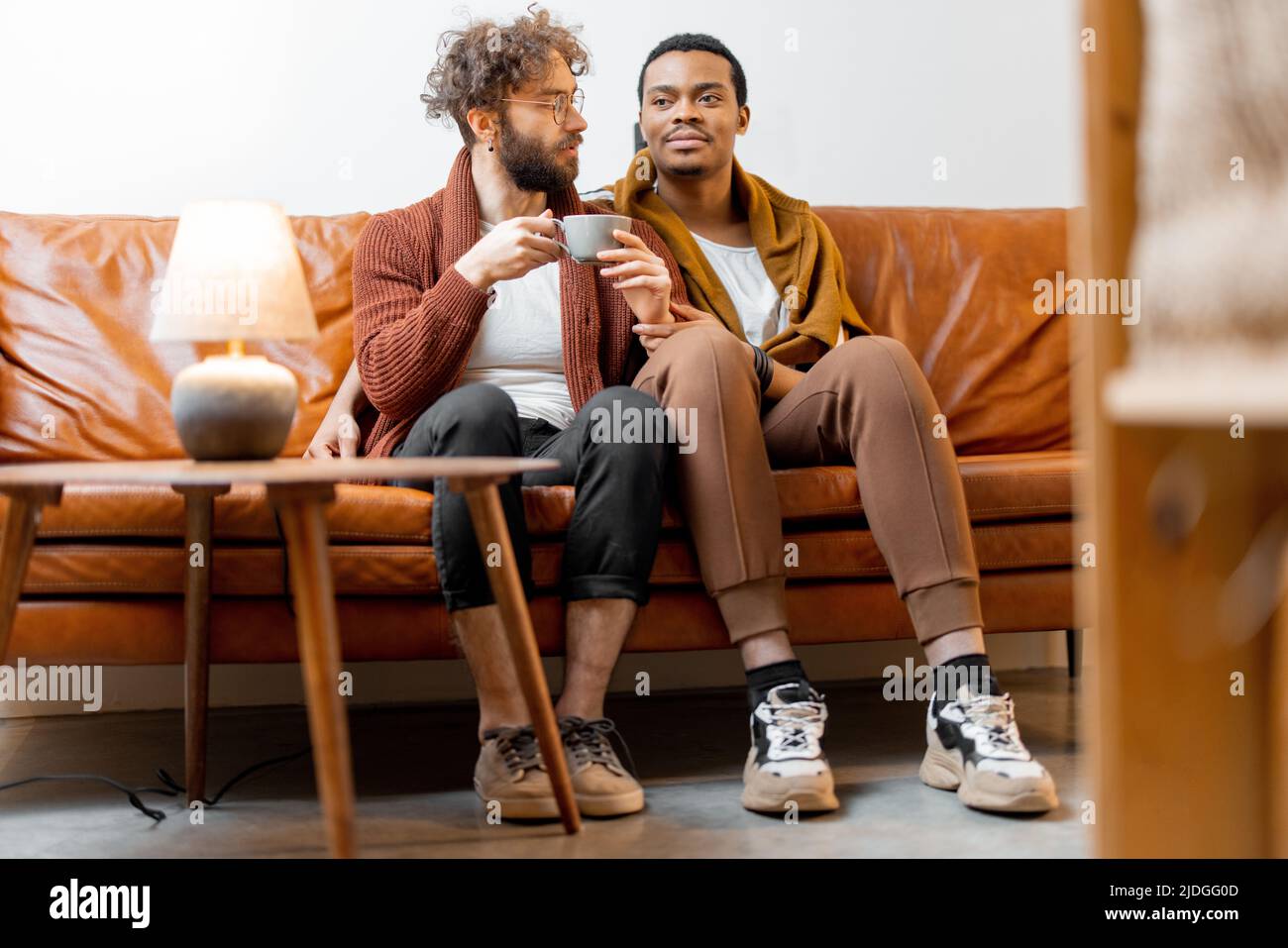 Un couple gay masculin parle sur un canapé à la maison Banque D'Images