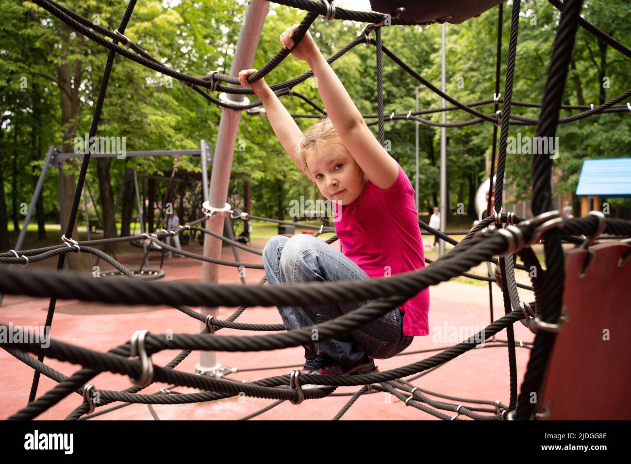 Bonne adolescente fille enfant jouant dans la toile d'araignée de corde à l'aire de jeux. Enfants. Photo de haute qualité Banque D'Images