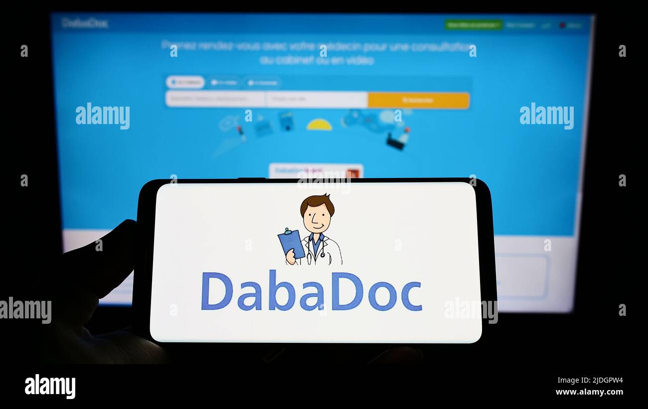 Personne tenant un smartphone avec le logo de la société marocaine de soins de santé DabaDoc à l'écran devant le site Web. Mise au point sur l'affichage du téléphone. Banque D'Images
