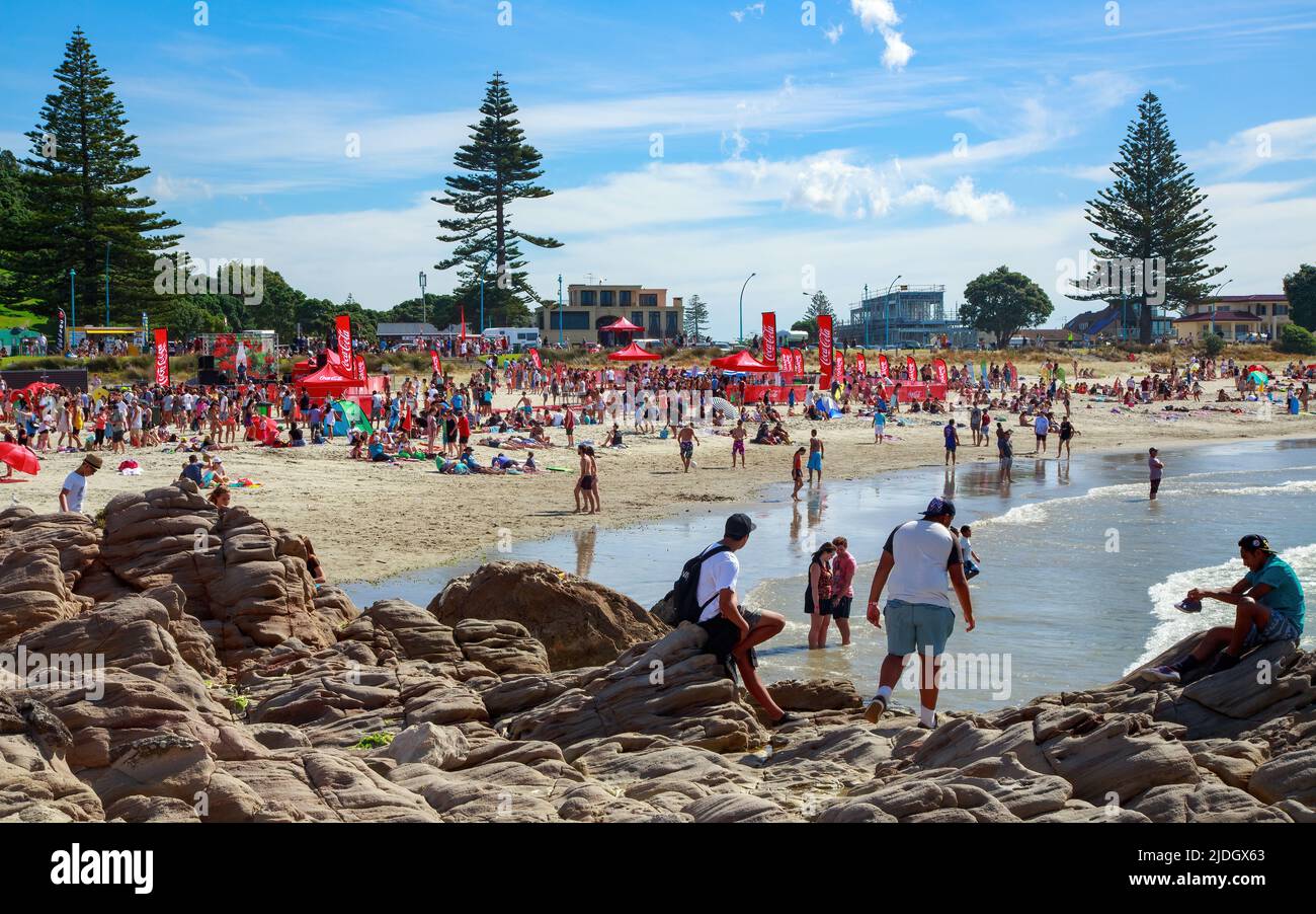 La plage du mont Maunganui, en Nouvelle-Zélande, un été chaud, bondée de gens et de bannières Coca-Cola d'un événement sponsorisé Banque D'Images