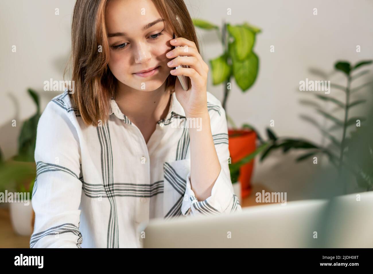 Belle femme d'affaires utilisant le téléphone au bureau à la maison. Espace de travail confortable, travail à distance, concept d'e-learning. Jeune heureux souriant femail parler sur téléphone portable organiser une réunion, partager des informations, fournir un soutien professionnel au client à l'aide de la technologie sans fil moderne et de la connexion. Banque D'Images