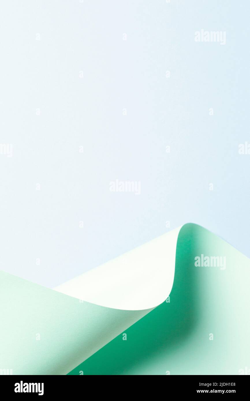 Vague abstraite de papier vert pastel sur fond bleu clair. Papier courbe géométrique créatif avec lumière et ombres. Arrière-plan de la géométrie abstraite Banque D'Images
