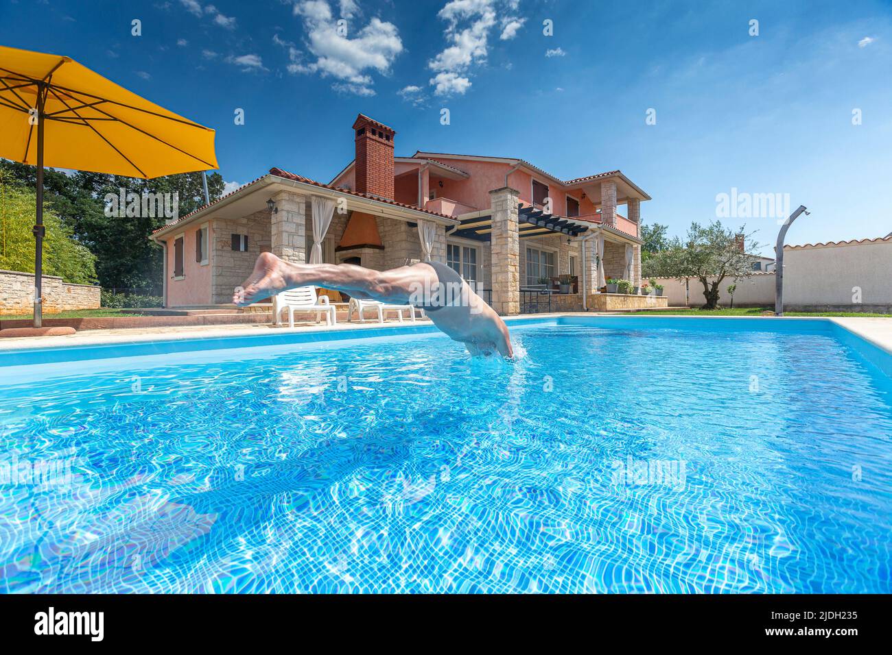Croatie, Istrie, Pula, homme senior sautant dans la piscine en face de la maison de vacances Banque D'Images