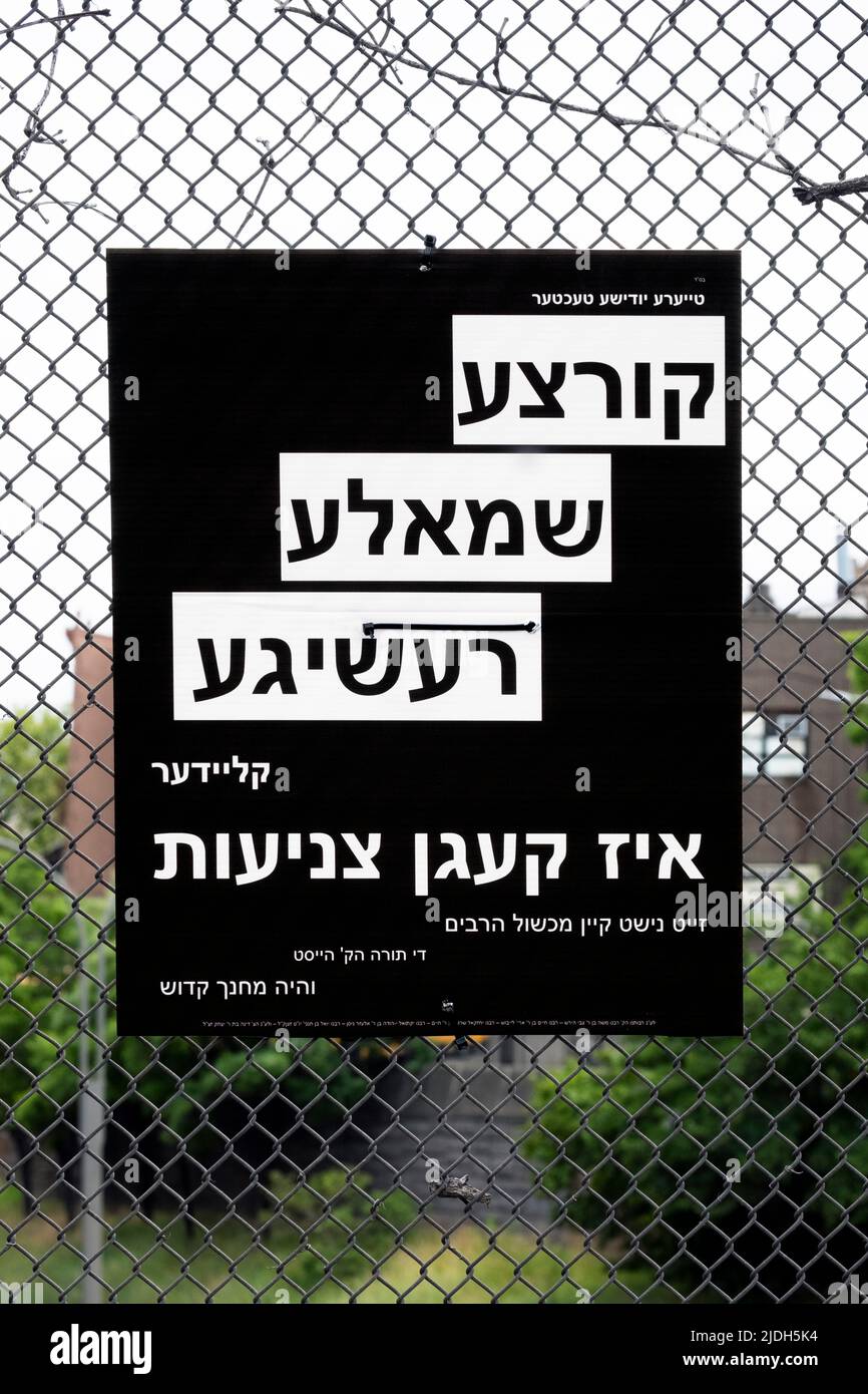 Un signe yiddish conseillant aux femmes juives observantes de s'habiller modestement. Sur Lee Avenue à Williamsburg, Brooklyn, New York. Banque D'Images