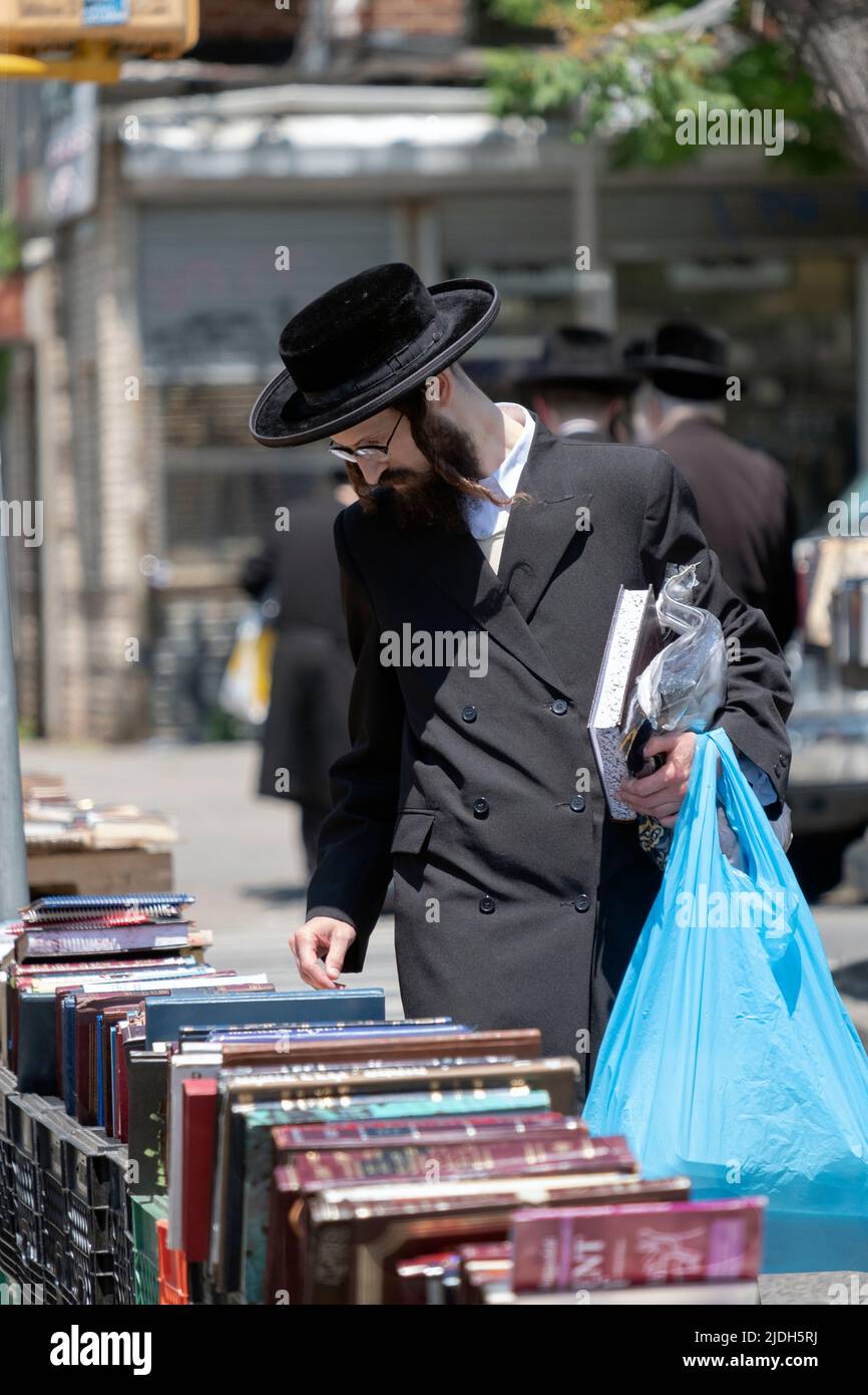 Un juif habillé de noir navigue à une vente extérieure de livres religieux. À Williamsburg, Brooklyn, New York. Banque D'Images