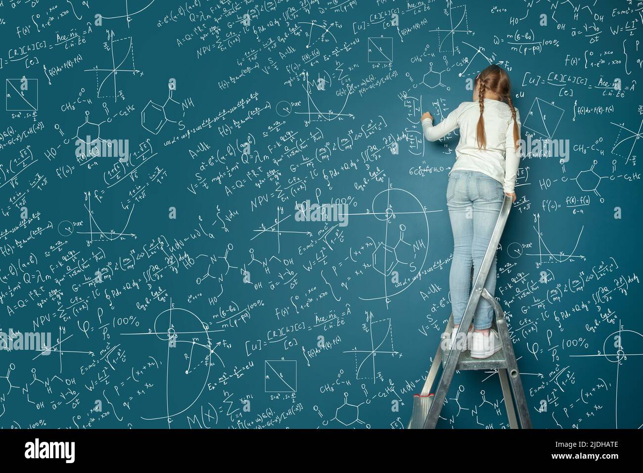 Portrait de fillette d'enfant heureux résoudre le problème mathématique complexe sur tableau bleu. Concept d'éducation mathématique pour enfants. Banque D'Images