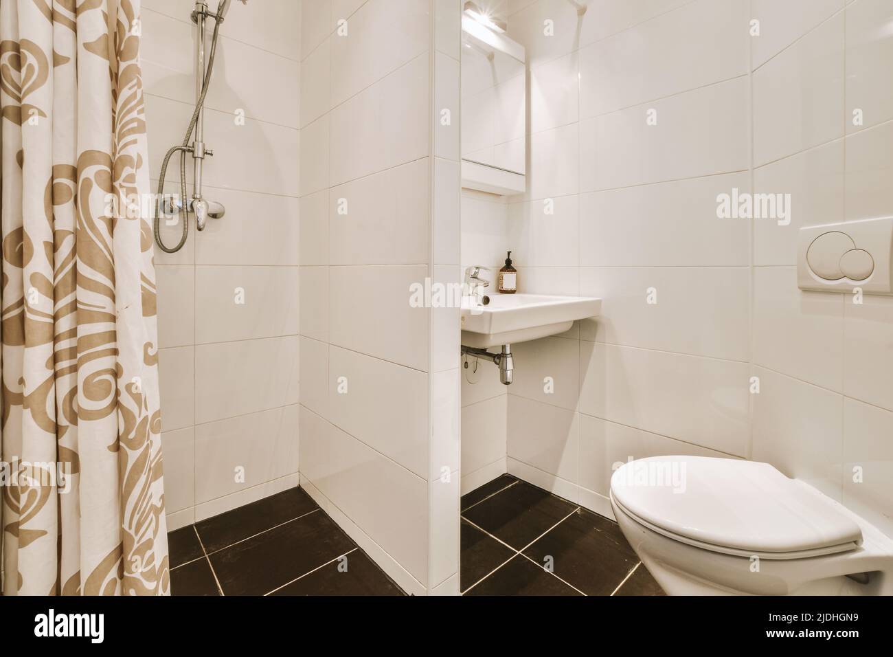 Lavabos avec miroirs et toilettes propres situés près de la boîte de douche avec porte en verre dans la salle de bains moderne avec murs carrelés blancs Banque D'Images