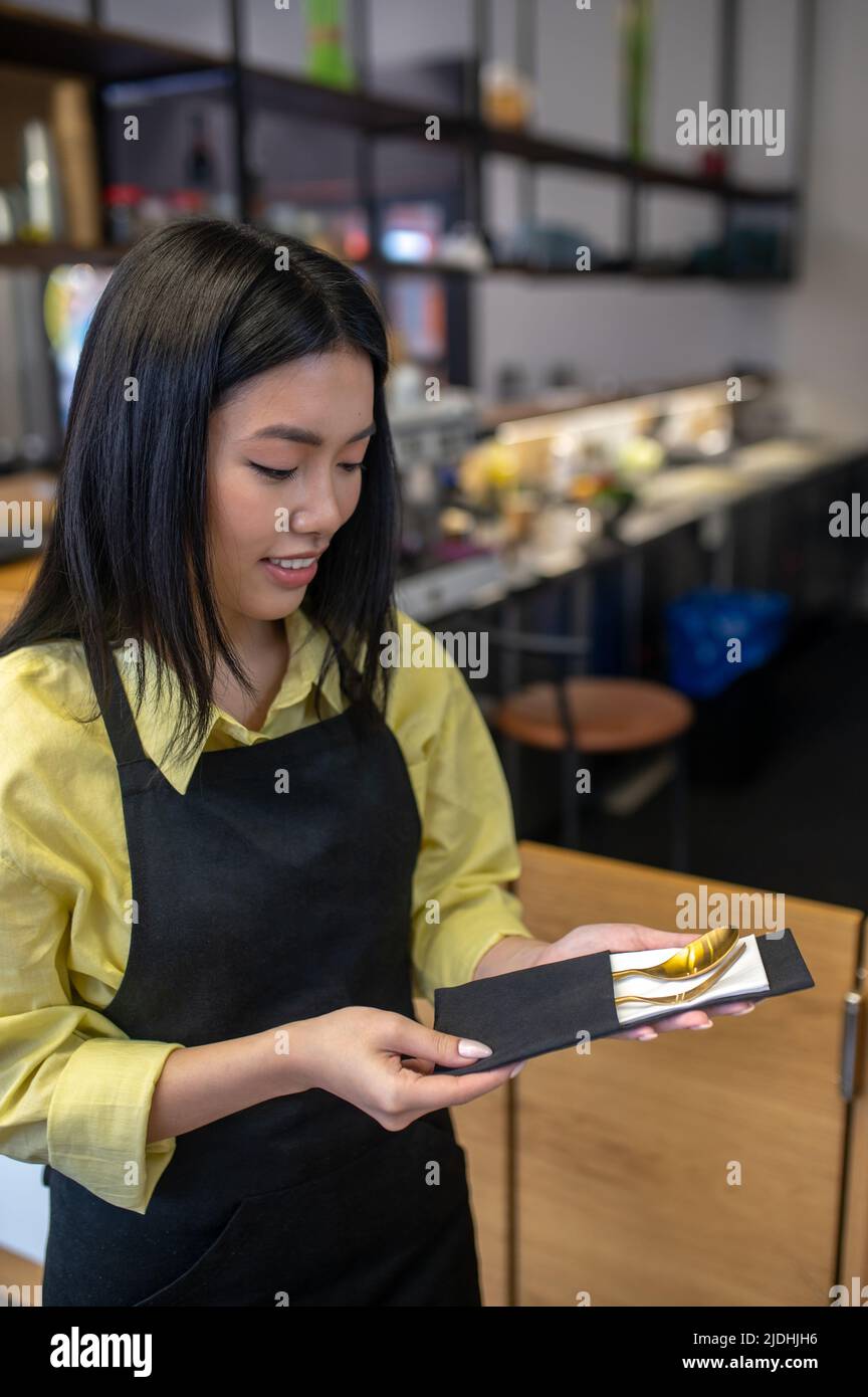 Femme regardant les couverts emballés dans une serviette Banque D'Images