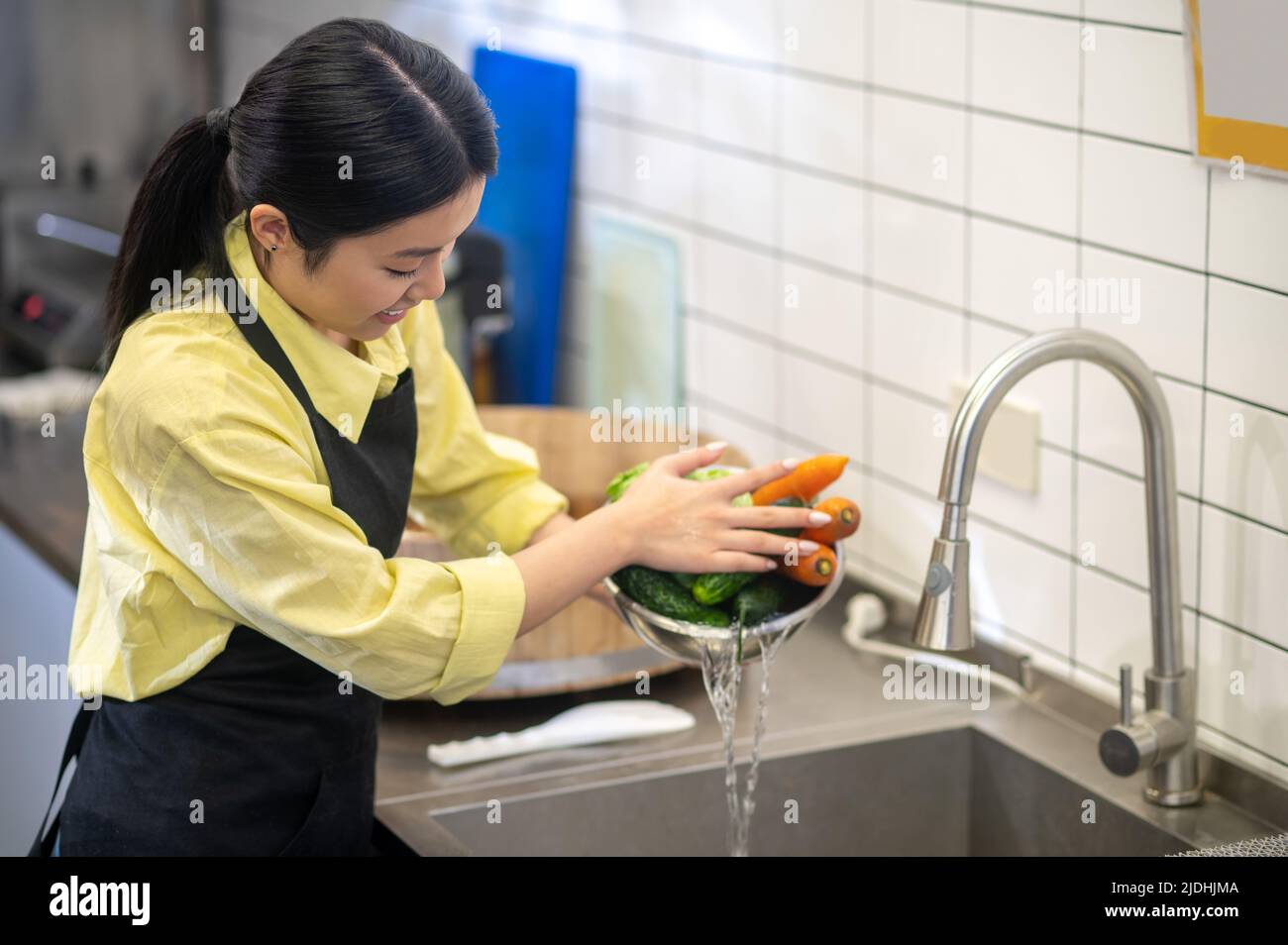 Femme qui vidange l'eau du bol de légumes Banque D'Images