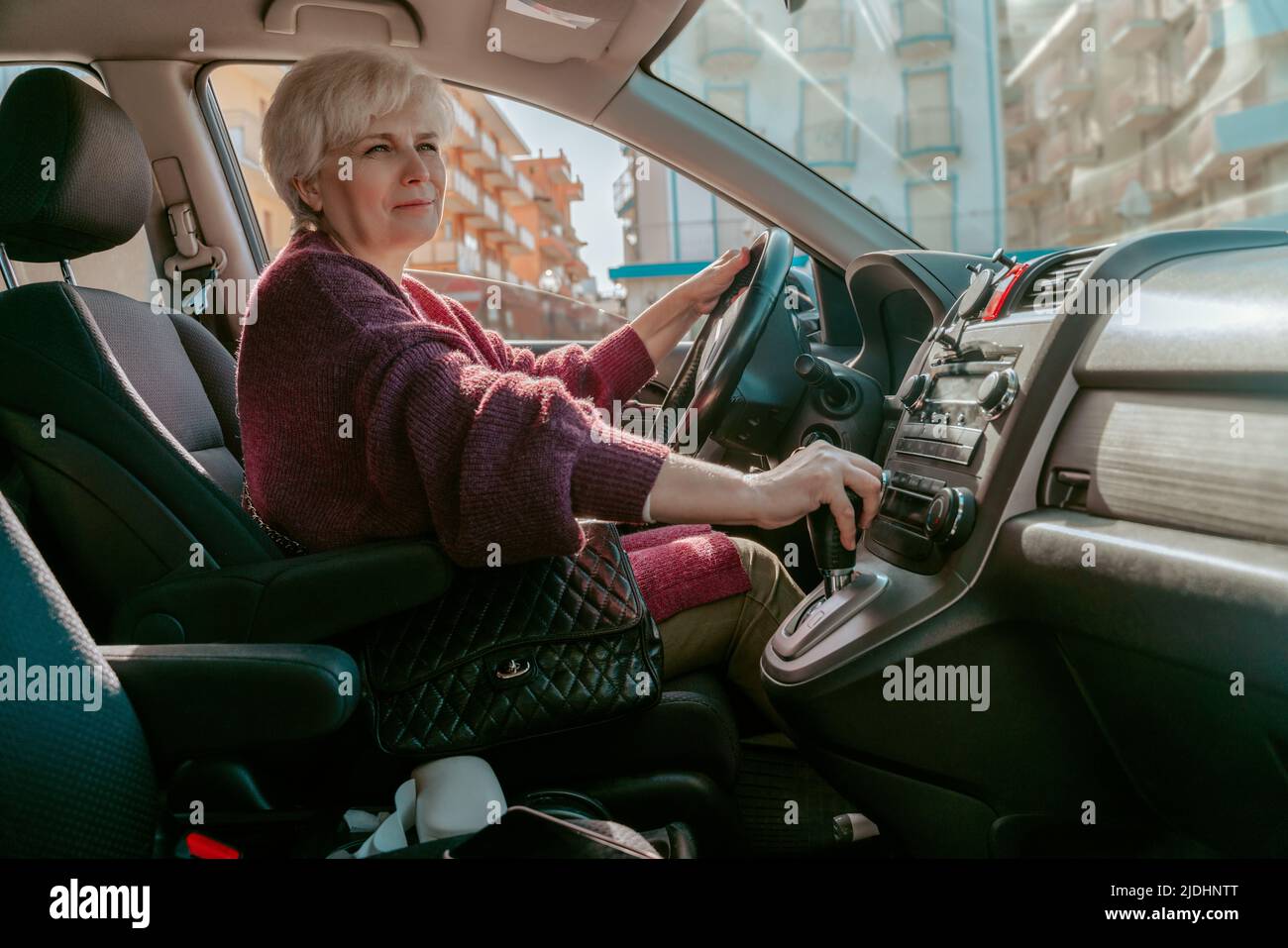 Femme aux cheveux gris assise dans la voiture de tourisme Banque D'Images