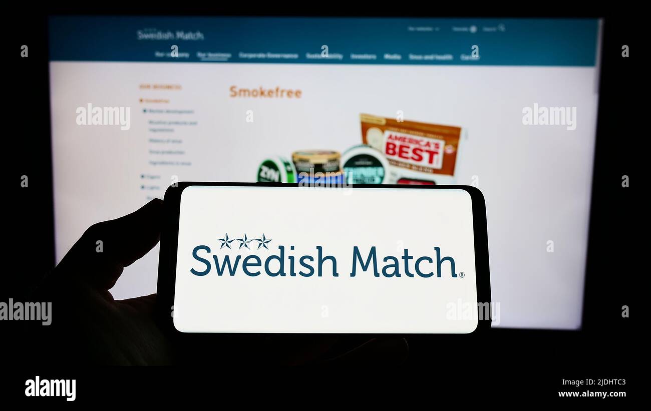 Personne tenant un smartphone avec le logo de la société de tabac Swedish Match AB sur l'écran devant le site Web. Mise au point sur l'affichage du téléphone. Banque D'Images