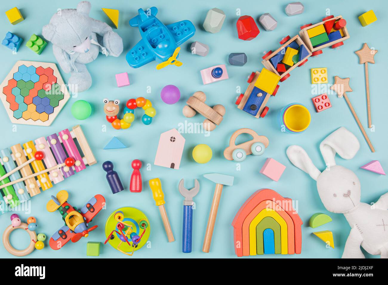 Motif de jouets pour bébés enfants. Ensemble de jouets éducatifs en bois et molletonnés colorés sur fond bleu clair. Vue de dessus, plan d'appartement Banque D'Images