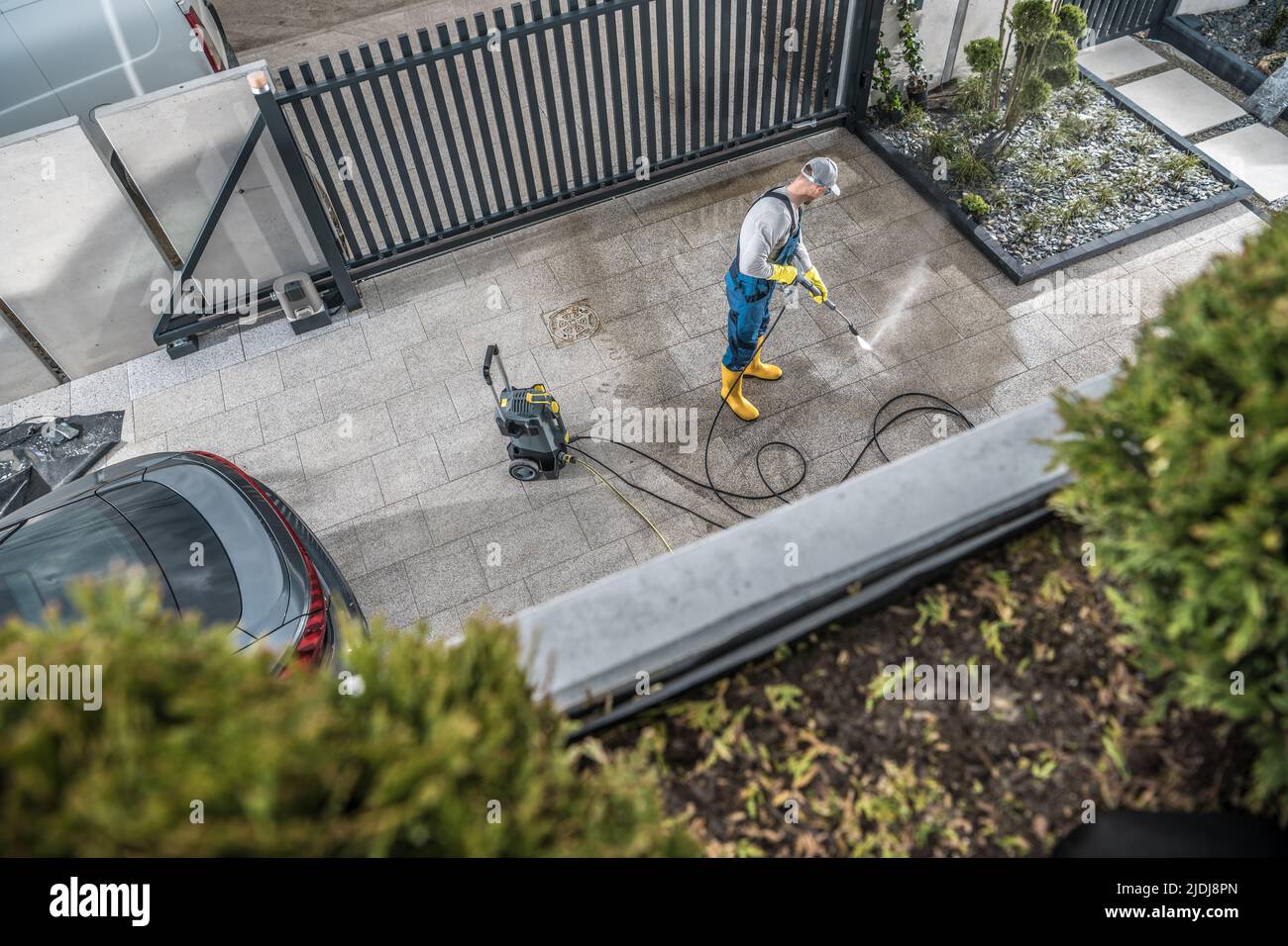 Caucasien Householder prenant soin de béton allée devant la maison en le nettoyant avec nettoyeur à pression. Entretien et entretien des biens personnels Banque D'Images
