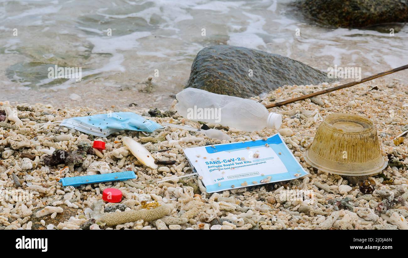 Utilisé masque réutilisable avec test Covid, bouteille en plastique et autres déchets se trouvent sur la plage Banque D'Images