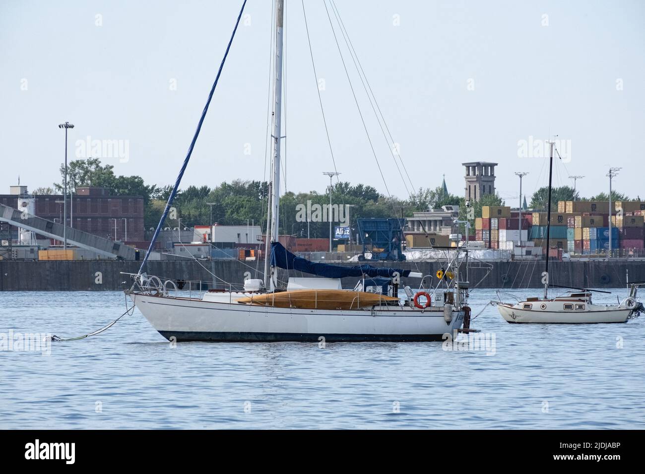 Deux voiliers dans le fleuve Saint-Laurent près du port de Montréal par temps chaud. Au loin, les conteneurs d'expédition sont empilés par des grues. Banque D'Images