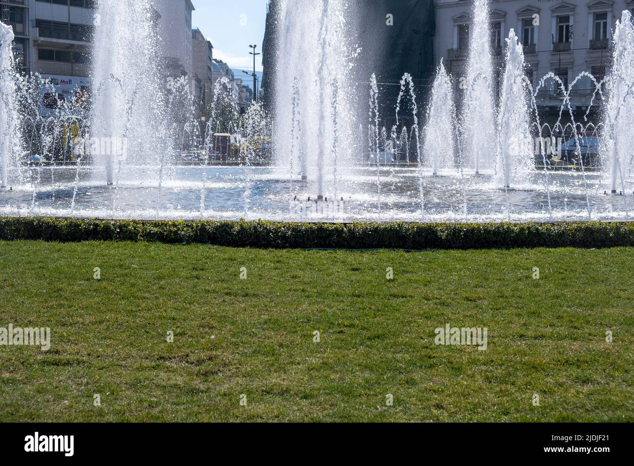 Fontaine dans le centre-ville. Des jets d'eau décorent une place de ville de forme ronde, un petit étang et de l'herbe autour, jour ensoleillé, vue rapprochée Banque D'Images