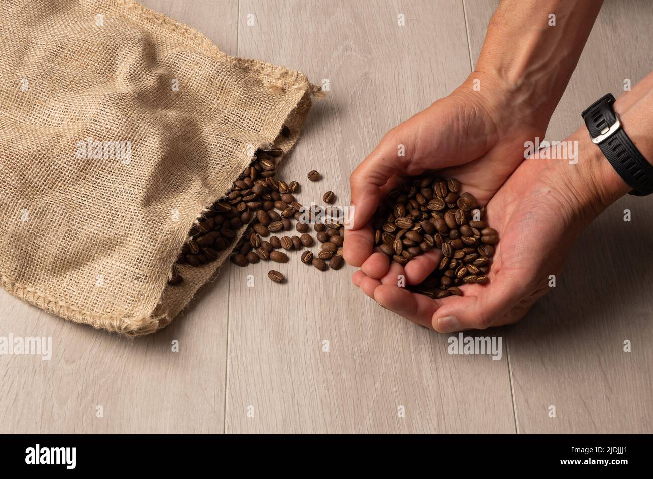 Grains de café moulus à la main et débordés d'un sac en toile de jute sur fond de bois clair Banque D'Images