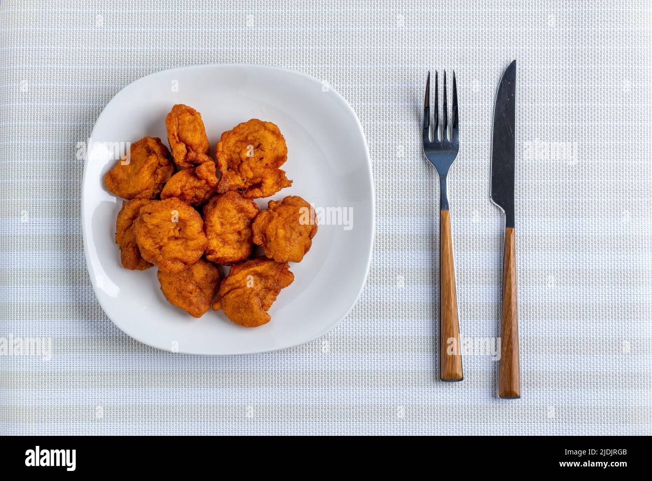 Des boules Akara dans une plaque en céramique blanche servies et flanquées d'une fourchette et d'un couteau Banque D'Images